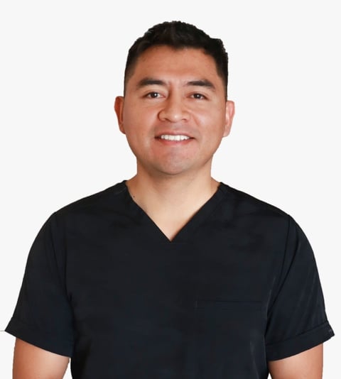 Man wearing black v-neck shirt smiling at camera with hands clasped in front against white background