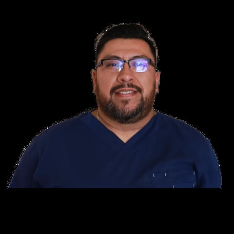 Man with dark hair and beard wearing glasses and a navy blue v-neck shirt against a black background