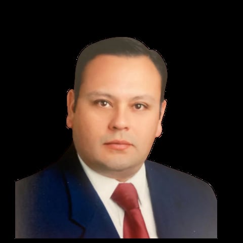 Professional headshot of a man wearing a dark blue suit jacket and red tie against a black background