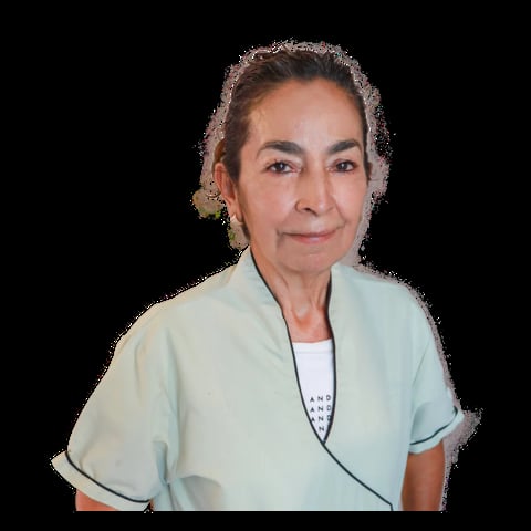 Middle-aged woman with gray hair pulled back, wearing a light blue short-sleeved wrap top over a white shirt, against a black background