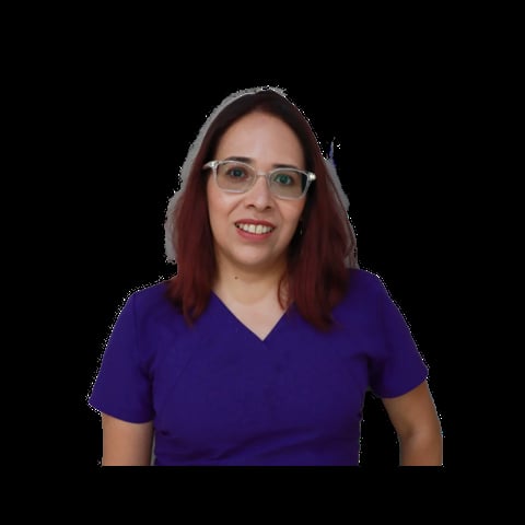 Woman with burgundy hair and glasses wearing a purple v-neck shirt against a black background