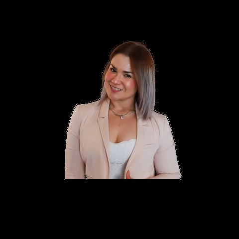Woman with long brown hair wearing a beige blazer and silver necklace, smiling against a black background