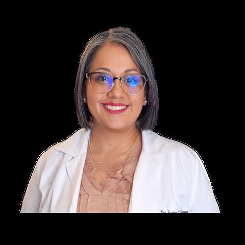 Woman wearing blue-tinted glasses and white blazer over beige top, smiling at camera against black background