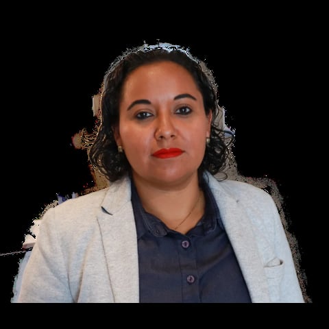 Woman with dark curly hair wearing a light cardigan over a dark shirt, with red lipstick and a slight smile, against a black background.