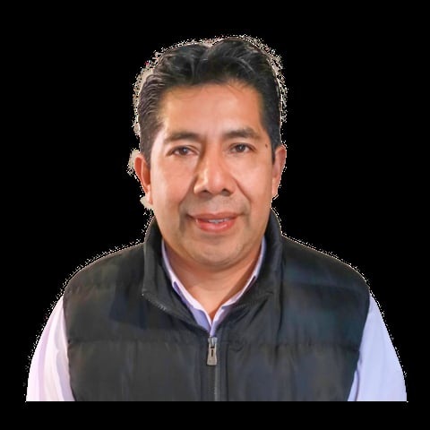 Middle-aged man with dark hair wearing a black puffer vest over a light blue shirt, smiling at the camera against a black background