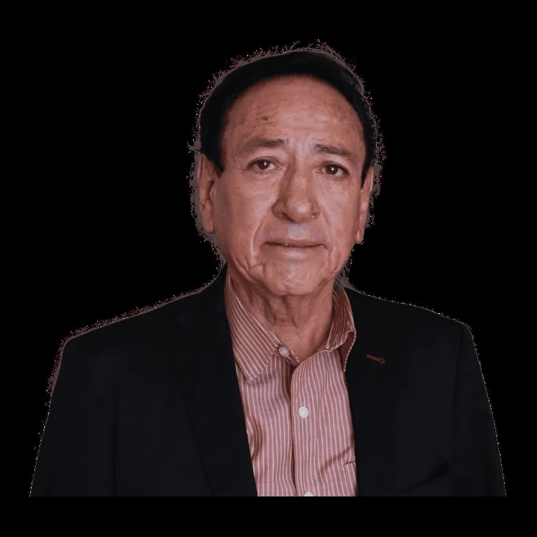 Portrait of an older man wearing a black blazer and pink striped shirt against a black background