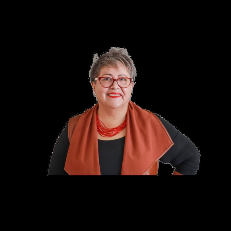 Professional headshot of a woman with short gray hair, glasses, and red lipstick wearing a black top with a rust-orange cardigan