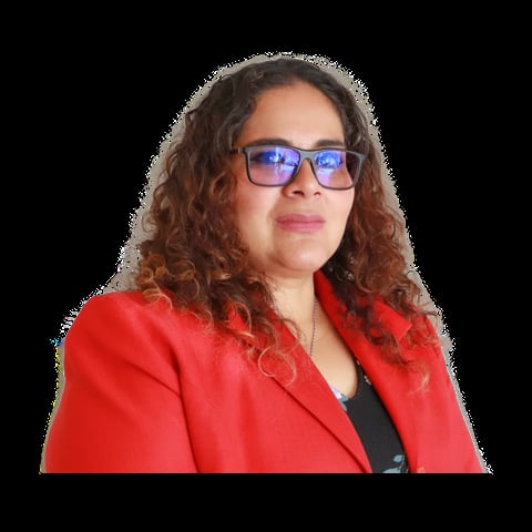 Woman with long curly reddish-brown hair wearing blue-tinted glasses and a bright red blazer over a black top