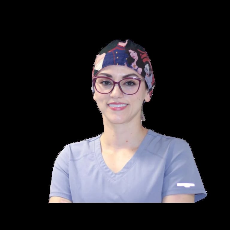 Woman wearing glasses and a blue scrub top with a patterned surgical cap, smiling at camera