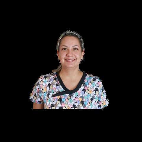 Professional headshot of a smiling woman wearing a colorful patterned short-sleeve shirt with black trim against a black background