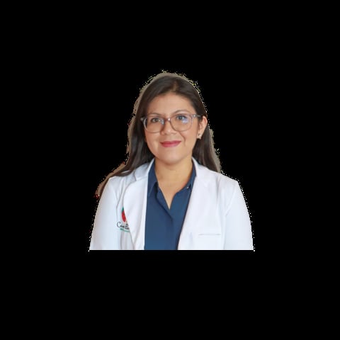 Female doctor wearing glasses and white lab coat over dark blue scrubs, smiling at camera against black background.