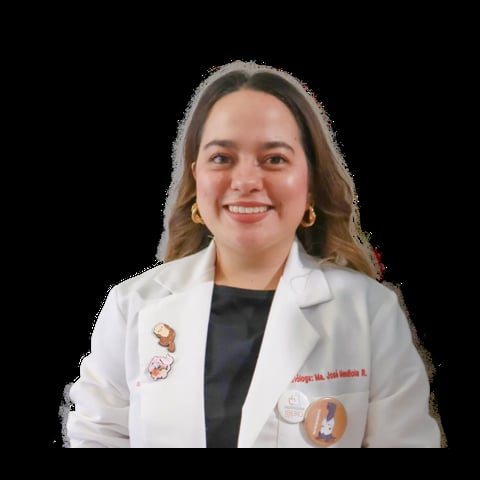 Professional headshot of a woman wearing a white medical coat over a black shirt, smiling at the camera against a black background.
