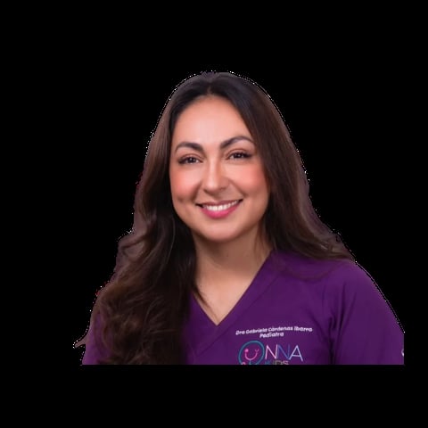 Professional headshot of a smiling woman with long dark hair wearing a purple medical scrubs top against a black background